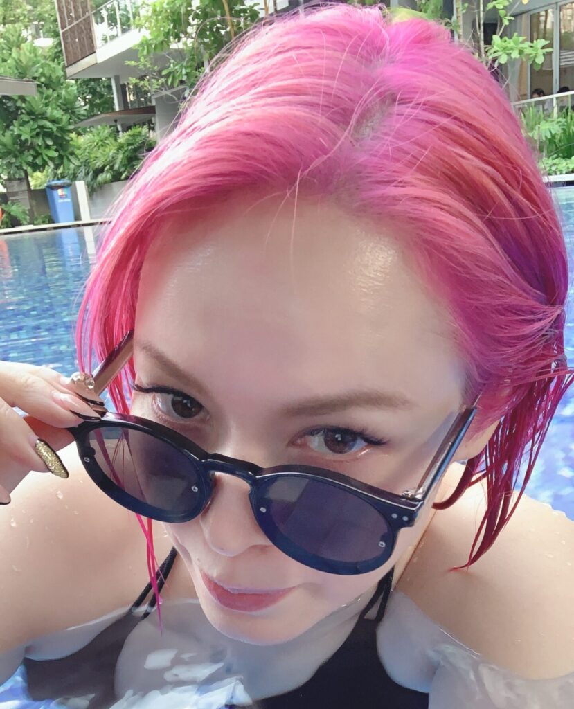 ピンクの髪にサングラスをかけてプールで寛ぐ伊藤クリスi
